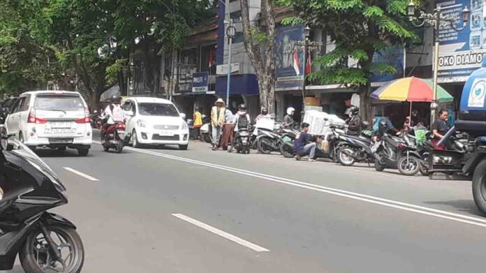 Jukir di Pasar Cakranegara mengatur kendaraan yang parkir pada Rabu 4 September 2024. Dinas Perhubungan akan menaikkan tarif retribusi parkir kendaraan seiring meningkatnya target parkir di Kota Mataram. (ekbisntb.com/cem)