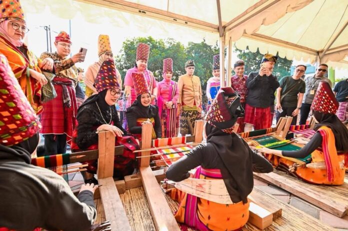 Ketua Dekranasda NTB Sinta M. Iqbal bersama Sekda KLU, Sahabudin, Asisten Deputi Event Daerah pada Kemenpar, Reza Fahlevi, Ketua GOW KLU, RR. Pungky Kusmalahadi Syamsuri, jajaran OPD serta para pemuka adat melihat secara langsung proses pembuatan tenun khas KLU. (Suara NTB/ist) Mulud Adat Bayan Masuk Kharisma Event Nusantara